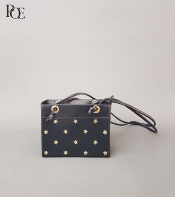 un sac à main noir orné d'étoiles dorées, posé sur une surface blanche