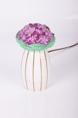 un vase blanc contenant des fleurs violettes, posé sur une table