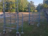 three metal scaffoldings in a field with trees in the background