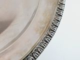 a close up of a silver plate on a white surface