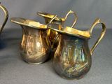two silver pitchers with handles on a gray background
