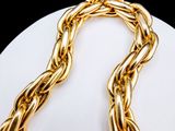 a close up of a gold chain necklace on a white plate