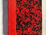 un livre rouge et noir posé sur une table blanche