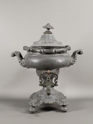 une théière ancienne en argent avec couvercle, posée sur un socle