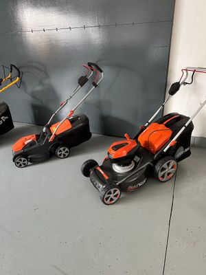 three lawn mowers are lined up against a wall in a garage