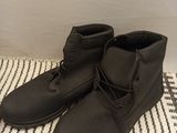 pair of black men ' s boots on a white and black striped rug