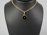 a gold necklace with a black stone pendant on a mannequin