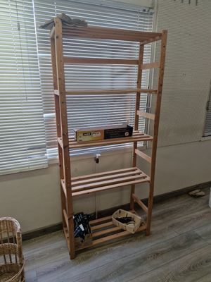 une étagère en bois dans un coin de la pièce, près d'une fenêtre