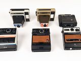 six polaroid cameras are lined up in a row on a white surface