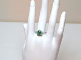 a hand with a ring on it that has a green stone on it