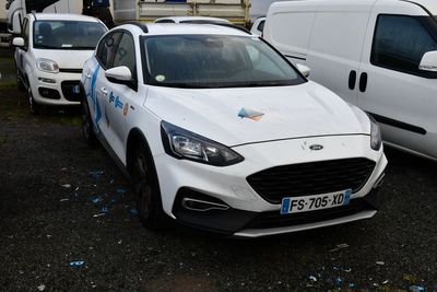 des voitures garées sur un parking à côté d'une camionnette blanche et d'une camionnette blanche