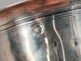 someone is holding a silver cup in their hand on a table