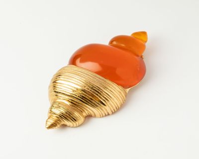 an image of a gold and orange shell broochle on a white surface