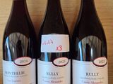 three bottles of red wine sit on a shelf in a wine shop