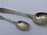 two silver spoons sitting on top of a table next to each other