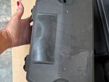 a person holding a black plastic box on top of a cardboard box