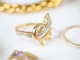 a gold ring with diamonds on a white table