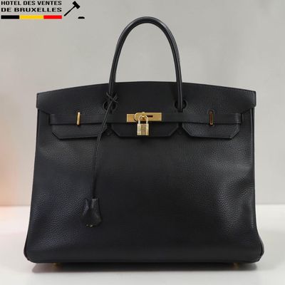 un sac à main en cuir noir muni d'un fermoir doré sur la poignée