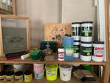 a shelf that has various paints and brushes on it