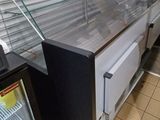 a refrigerated counter with a glass case on it