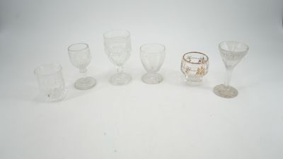 Plusieurs verres à pied et tasses sont alignés sur une surface blanche