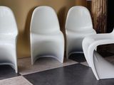 trois chaises en plastique blanc sont alignées sur un sol à carreaux