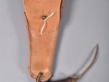 un vieux fourreau en cuir contenant un couteau, posé sur une surface grise