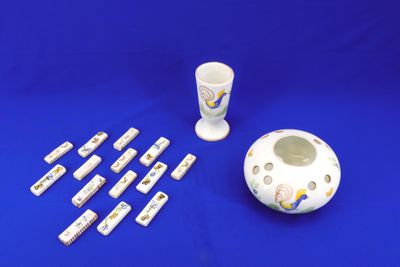 un vase blanc, une tasse et un jeu de dominos sur fond bleu