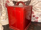a small red box sitting on the floor next to a vase