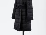 un manteau noir posé sur un mannequin, devant un fond blanc