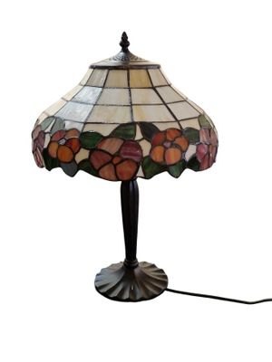une lampe dont l'abat-jour en vitrail repose sur une table
