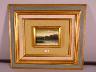 tableau représentant un paysage, encadré d'or, accroché à un mur blanc