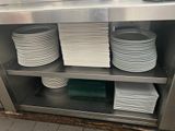 Plusieurs assiettes sont empilées sur une étagère métallique dans une cuisine