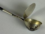 a silver spoon with a black handle on a white surface