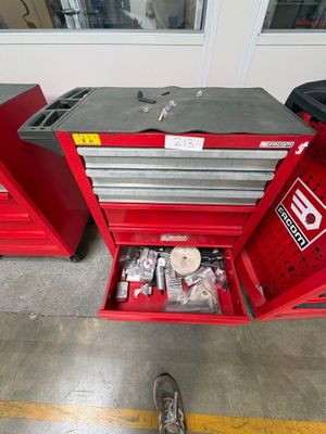 une boîte à outils rouge contenant des outils, dans un garage
