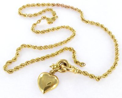a close up of a gold necklace with a heart on it