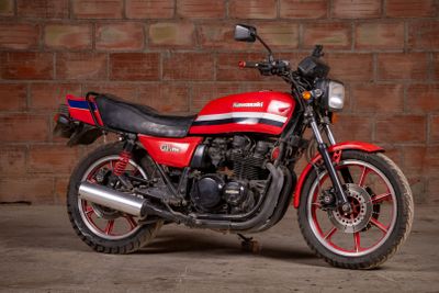 a red and black motorcycle parked in front of a brick wall