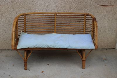 a wicker bench with a white cushion on it