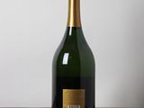 bottle of champagne sitting on a wooden table against a white wall