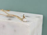 Le collier en or repose sur un bloc de marbre orné d'un diamant.
