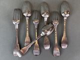 six forks and spoons are lined up on a gray surface