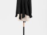 une chemise noire posée sur un présentoir à mannequin, sur fond blanc