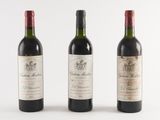 three bottles of wine are lined up on a white surface