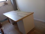 un bureau avec un plateau en bois, dans un coin de la pièce