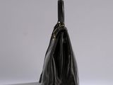 a black handbag sitting on top of a table next to a white wall