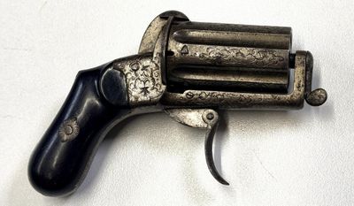 un vieux pistolet avec une poignée en bois sur une surface blanche