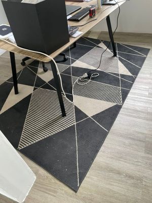 un tapis noir et blanc posé au sol, sur lequel se trouve un ordinateur portable