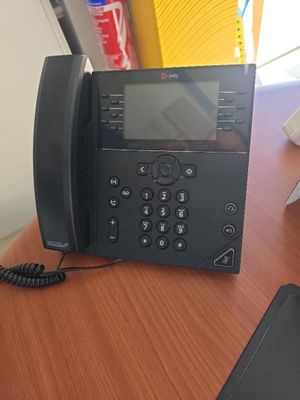 un téléphone noir posé sur un bureau en bois, à côté d'un téléphone portable