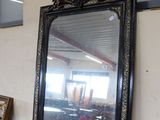 a large mirror sitting on a table next to a vase of flowers