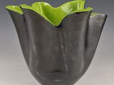 a close up of a black and green vase on a table